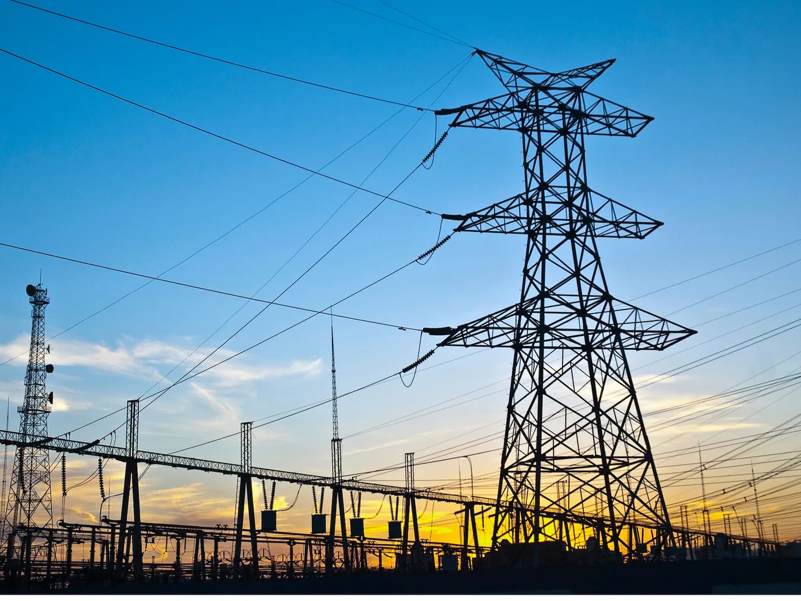 Torre de transmisión de alta tensión en una subestación eléctrica al atardecer