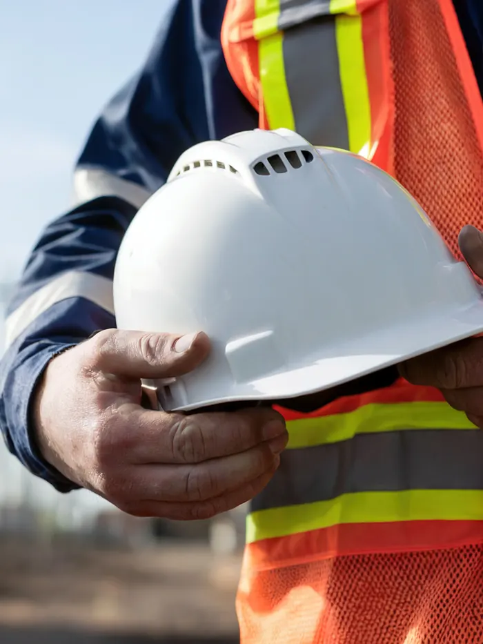 Supervisor con chaleco de seguridad sosteniendo un casco