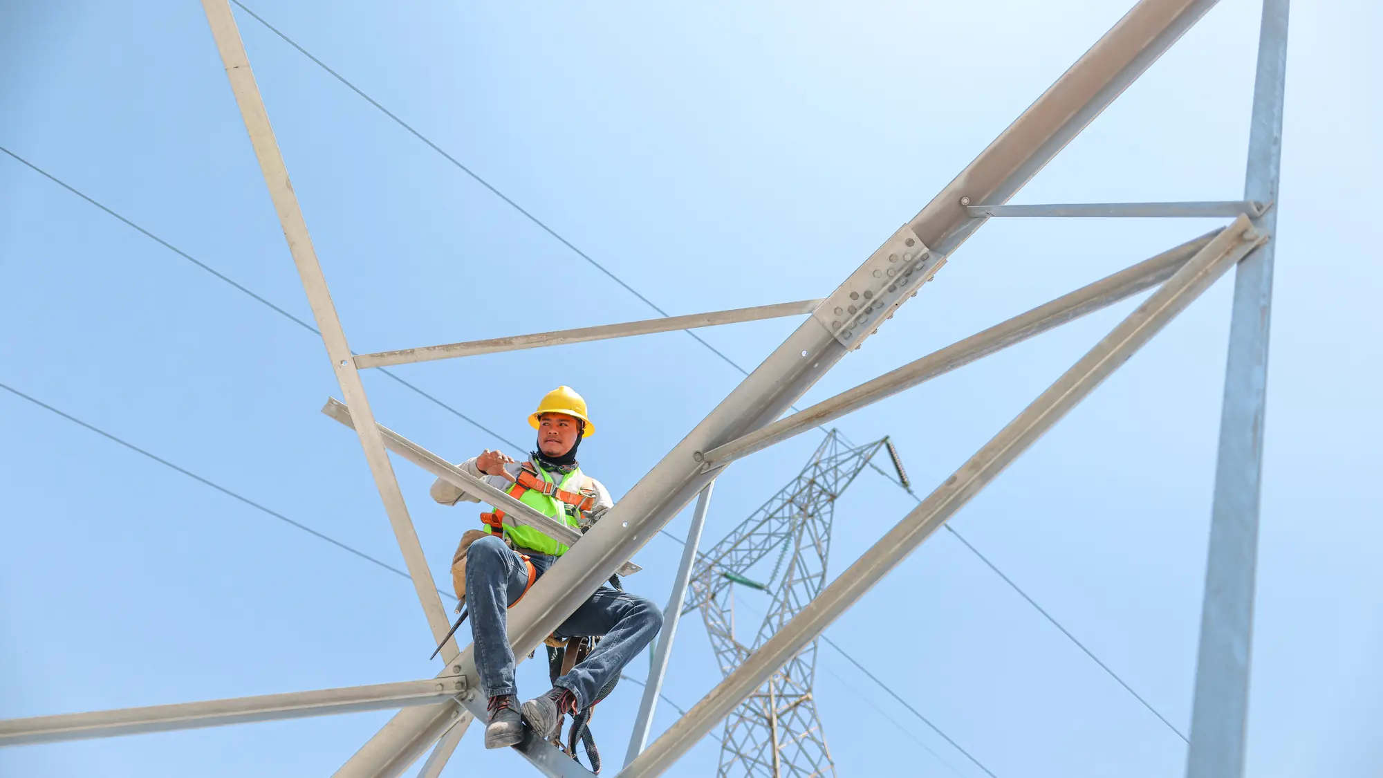 Liniero de HAESA trabajando en lo alto de una torre de transmisión de alta tensión